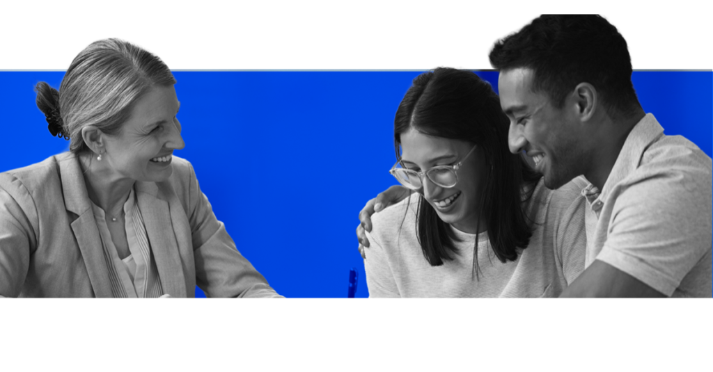 Mentora sorrindo para dois profissionais mais jovens que riem juntos, em fotografia a preto e branco sobre fundo azul